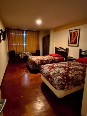 A room with two beds, a desk, a chair, a wardrobe, and a painting on the wall. - Hotel Berlina (La Paz)