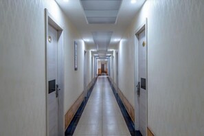 Un largo y estrecho pasillo de hotel con puertas a ambos lados, que conduce a una zona central.