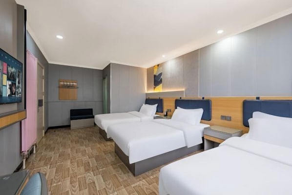 Habitación de hotel con cuatro camas, un escritorio, una silla, un televisor y una obra de arte colgada en la pared.
