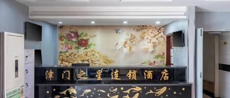 A reception desk with a floral mural and a black counter with gold accents.
