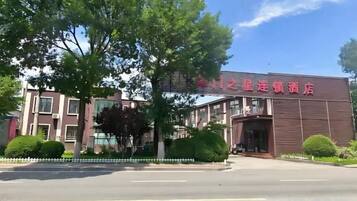 A building with a sign in a foreign language, surrounded by trees and a clear sky.