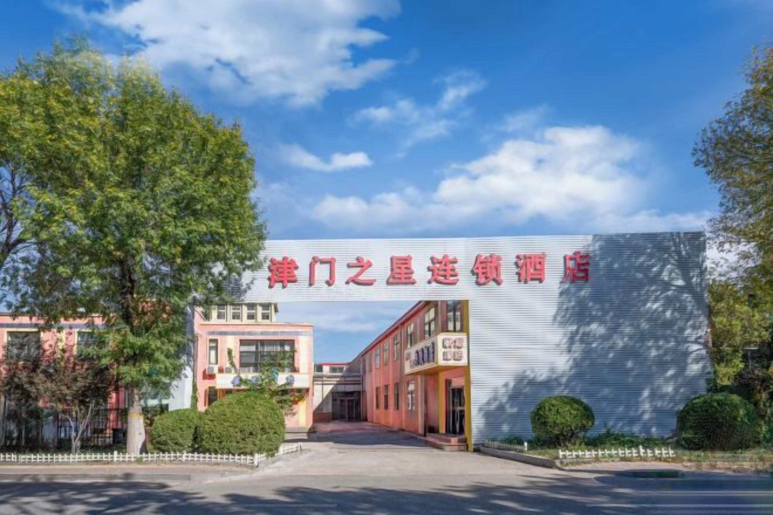 A hotel entrance with a large sign, a pathway leading to the entrance, and a clear sky.