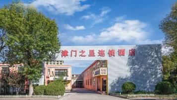 A hotel entrance with a large sign, a pathway leading to the entrance, and a clear sky.
