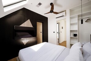 Un dormitorio moderno con cama, televisor integrado, ventilador de techo y vestidor.
