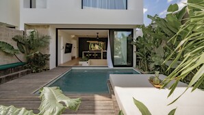 A modern house with a swimming pool, a dining area, and lush greenery. - Club Suma Villa 5 Bingin (Pecatu)