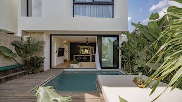 Een modern huis met zwembad, eethoek en weelderige beplanting.