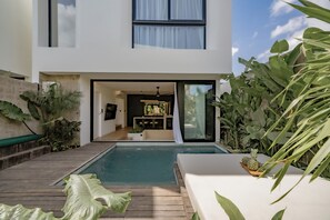 Ein modernes Haus mit Schwimmbad, Essbereich und üppiger Bepflanzung.
