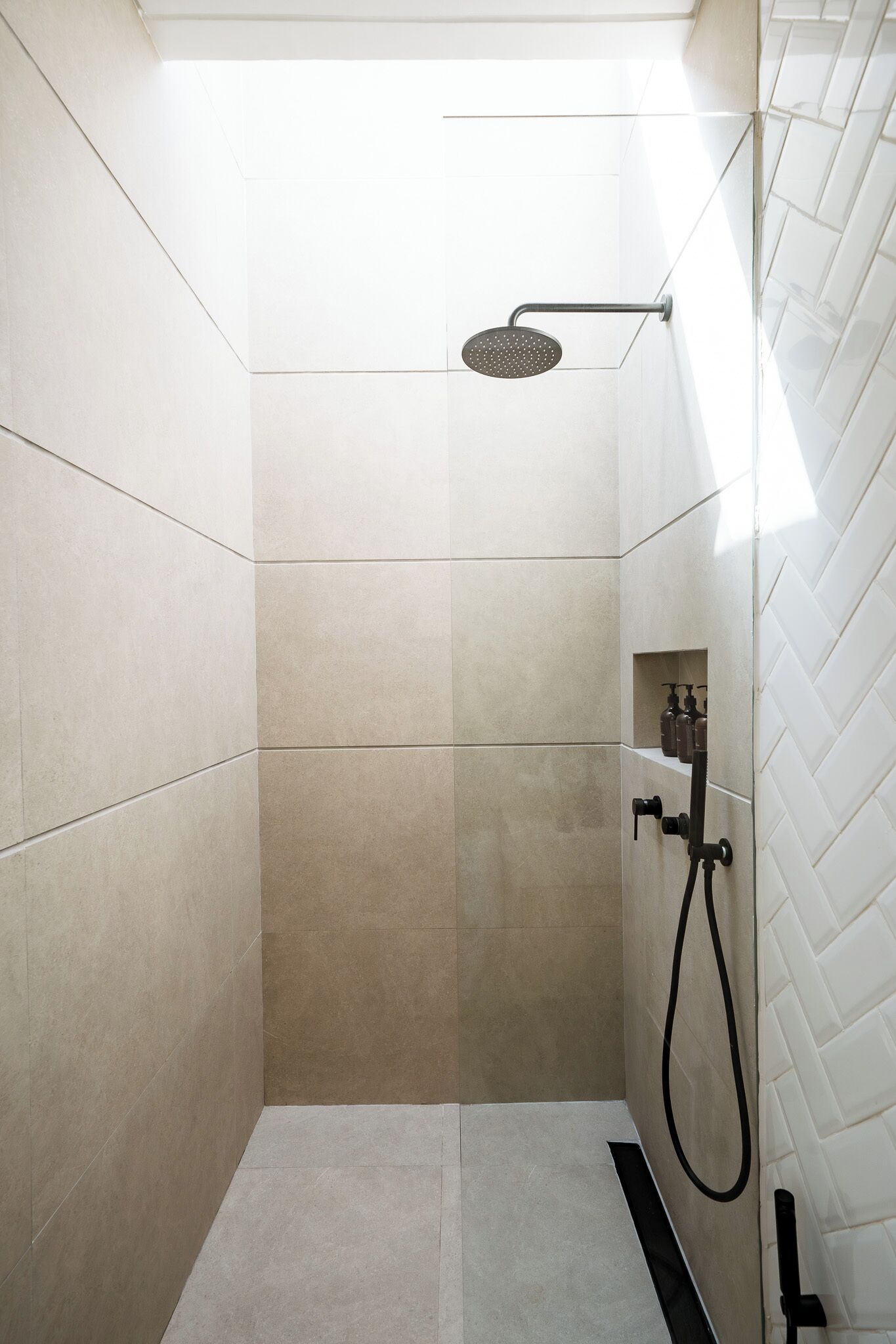 A small, enclosed shower area with a handheld showerhead and a handheld shower attachment.