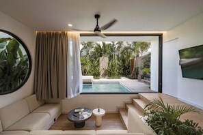 Una sala de estar moderna con vista a la piscina, un ventilador de techo y un televisor montado en la pared.