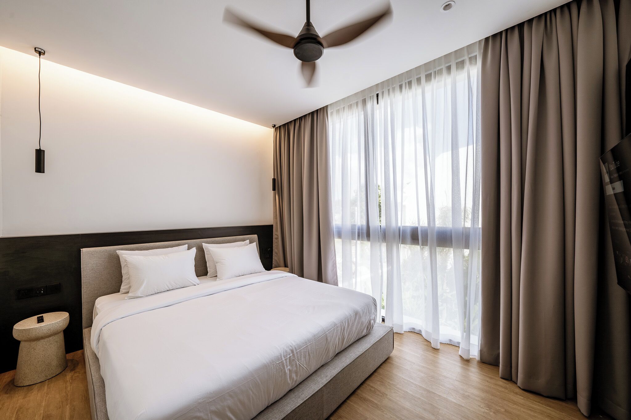 Una camera da letto moderna con un letto grande, una ventola a soffitto e tende leggere.