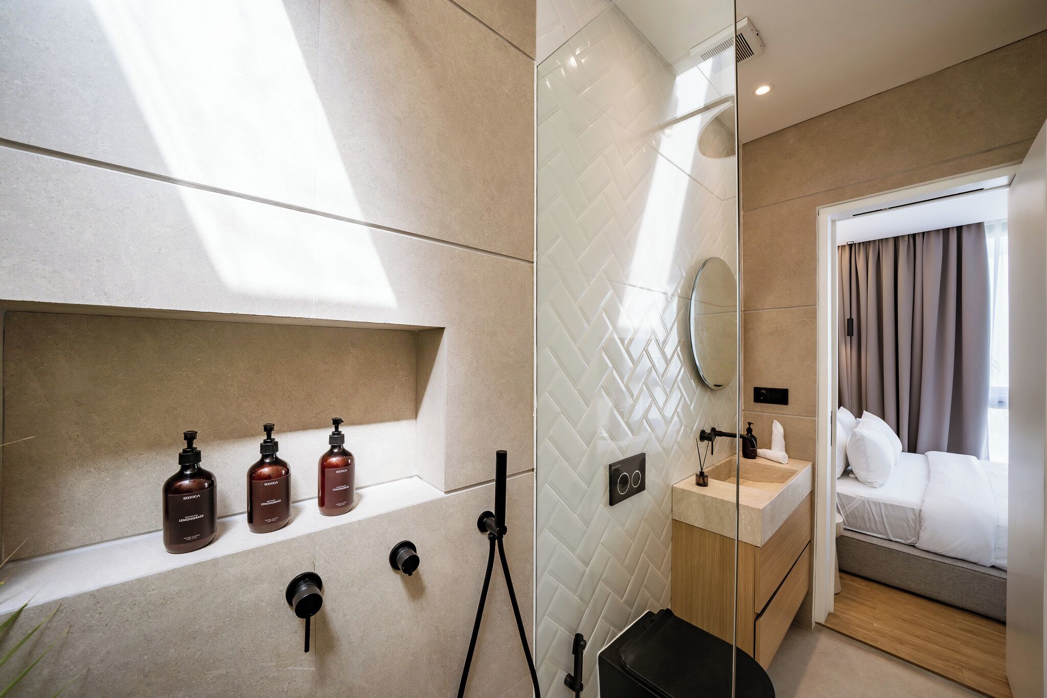 Un baño moderno con ducha, tocador con artículos de aseo y cama con cortinas.