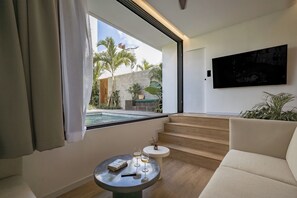 Ein modernes Wohnzimmer mit Blick auf einen Pool, einem Flachbildfernseher und einer Treppe, die zu einem Außenbereich führt.
