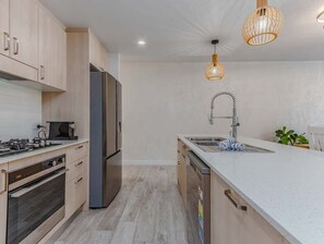 Eine moderne Küche mit Edelstahlkühlschrank, Backofen und einer großen Kücheninsel mit Spüle.