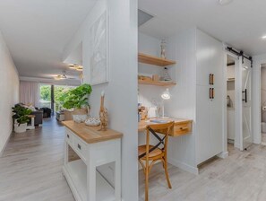 Eine moderne Küche mit weißen Schränken, einer Holz Arbeitsplatte und einem Essbereich mit einem Stuhl.