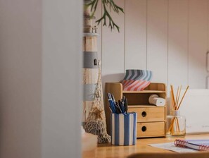 A wooden desk with a striped pen holder, a small plant, and a lamp. - Forever Summer at Drift North (Tweed)