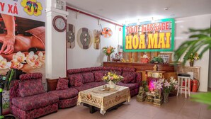 A massage parlor with a sofa, a table with flowers, and a sign that reads 'Fout Massage Hoa Mai'. - New Hotel Vung Tau (Ho Chi Minh City)