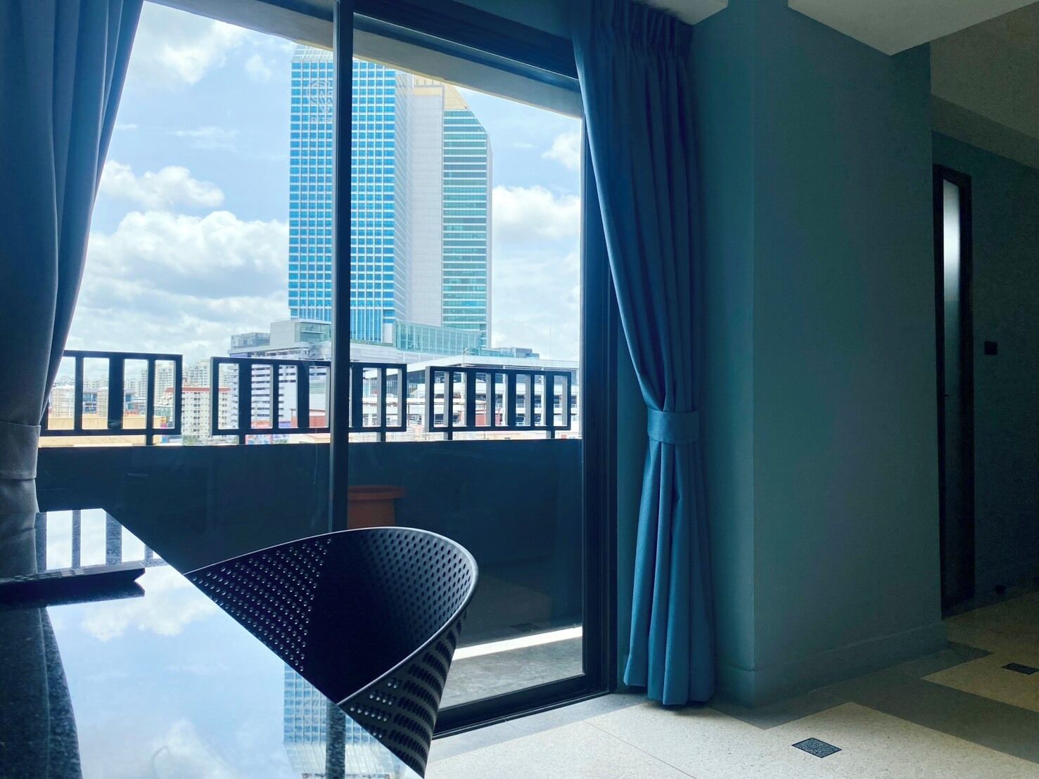 Una habitación de hotel moderna con un ventanal grande, un balcón y un rincón de comedor.