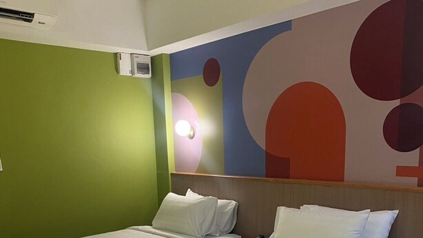 A hotel room with two beds, a green wall, and a large abstract painting. - Witz Pop Ratchada (Bangkok)