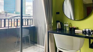 A room with a balcony, a round mirror, a table with a chair, and a view of a cityscape. - Witz Pop Ratchada (Bangkok)