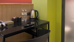 A small hotel room with a single table, two chairs, a kettle, a water bottle, and a remote control. - Witz Pop Ratchada (Bangkok)