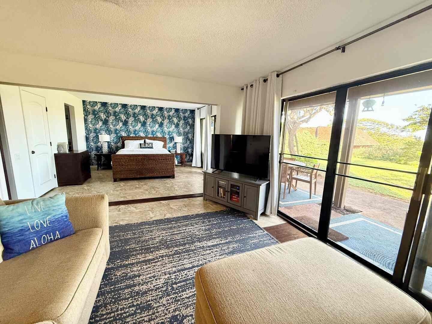 A modern hotel room with a bed, TV, sofa, and a balcony with a view.
