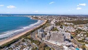 Un paysage urbain côtier avec des hôtels en bord de mer, des routes et un ciel bleu dégagé.