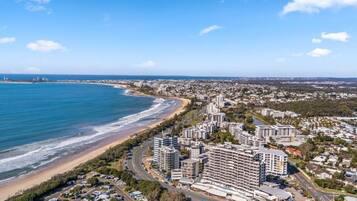 A coastal cityscape with beachfront hotels, roads, and a clear blue sky.