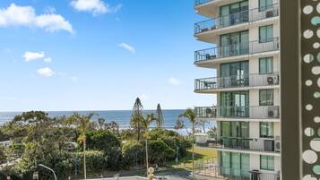 A multi-story building with balconies overlooking a beach and ocean.