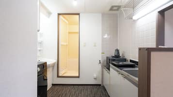 Un baño de hotel pequeño y funcional con inodoro, lavamanos y lavadora compacta.