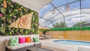 Uma área de piscina interna com teto de vidro, mobiliário de vime e uma bandeira com design em espiral.