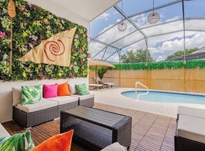 An indoor pool area with a glass ceiling, wicker furniture, and a flag with a spiral design. - Once Upon A Vacation Home with Pool + Game Room + Sleeps 9 near DISNEY! (Kissimmee)