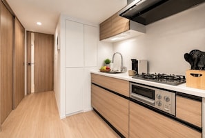 Eine moderne Küche mit Holzschränken, einem Edelstahlherd und einem eingebauten Backofen.