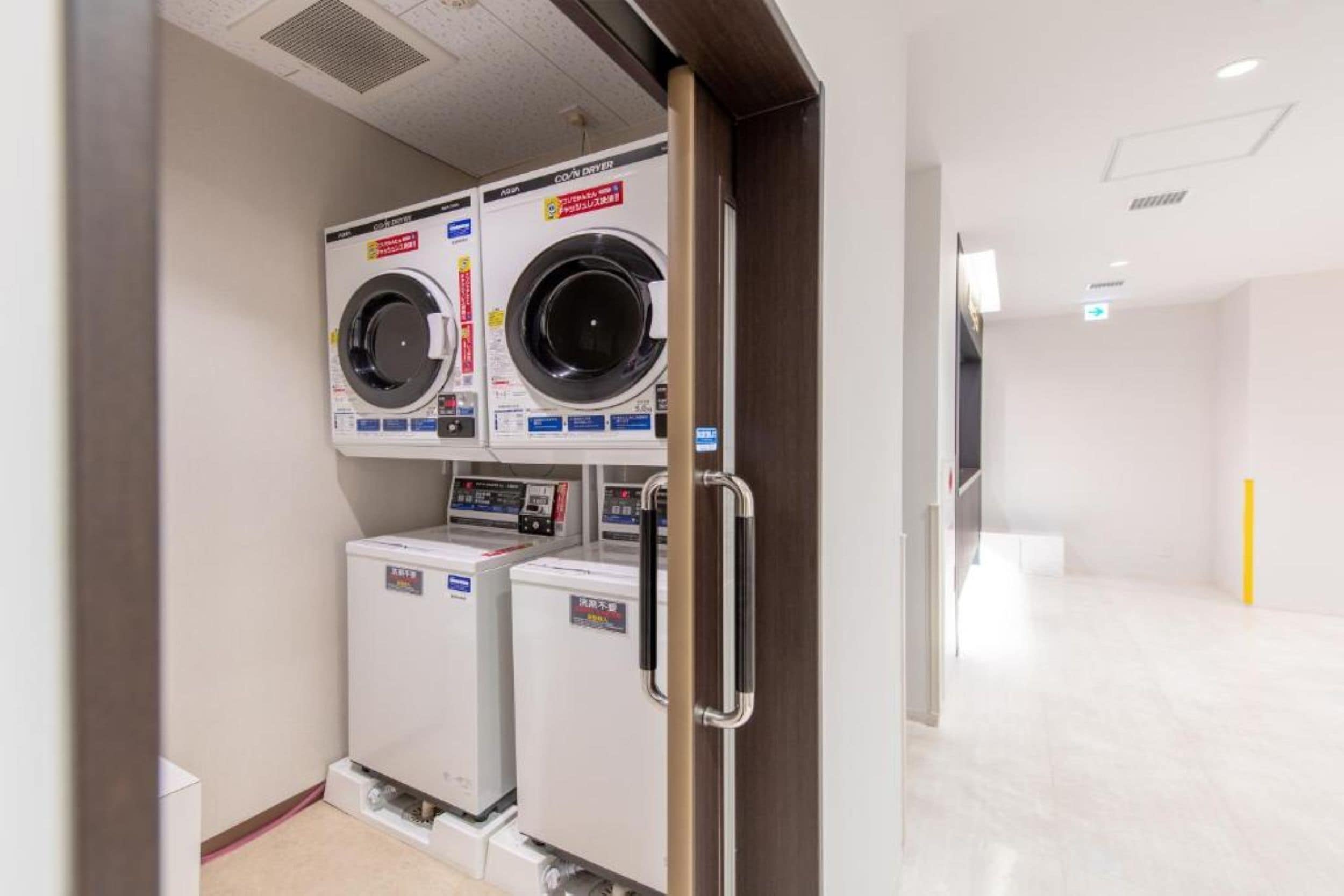 Une buanderie équipée de deux machines à laver superposées et d’un sèche-linge.