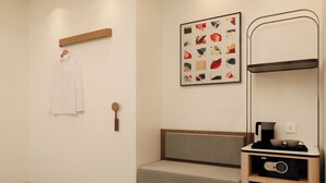 Een moderne badkamer met een houten bankje, een handdoek aan de muur en een lijst met abstracte kunst.