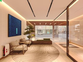 A modern interior with a reception desk, seating area, and a large window offering a view of the street.