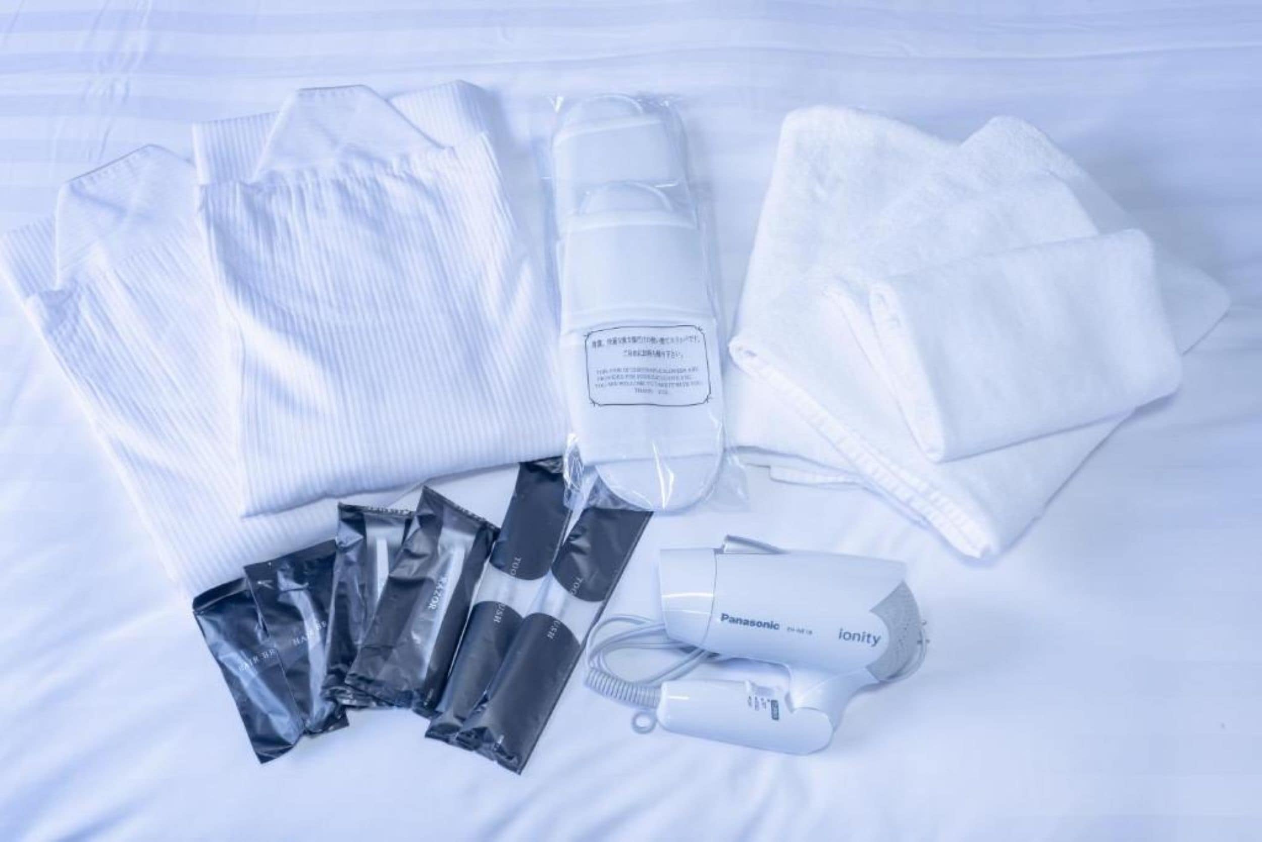 A neatly arranged set of toiletries and a hairdryer on a bed.