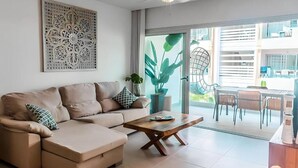 Ein modernes Wohnzimmer mit einer Couch, einem Couchtisch und einem großen Fenster.