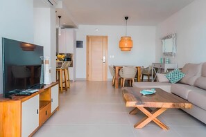 Ein modernes Wohnzimmer mit Fernseher, Couchtisch aus Holz und einer Couch.