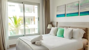 Ein Hotelzimmer mit Bett, Fenster mit Vorhängen und Blick auf ein Gebäude.