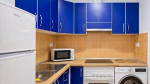 A compact kitchen with a microwave, sink, stove, and washing machine. - GuestReady - Rosamar P Apartments (Las Palmas de Gran Canaria)