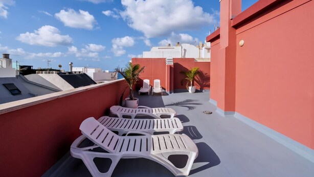 A rooftop terrace with white lounge chairs, potted plants, and a clear blue sky. - GuestReady - Rosamar P Apartments (Las Palmas de Gran Canaria)