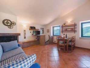 Ein gemütlicher Wohnbereich mit Kamin, Fernseher und Esstisch mit Stühlen.