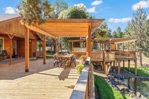 A wooden deck with outdoor furniture, a pergola, and a small pond.