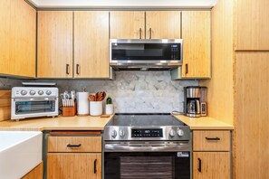 Une cuisine moderne avec des meubles en bois, un four à micro-ondes, une cuisinière et une machine à café.