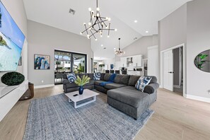 Ein modernes Wohnzimmer mit einem Ecksofa, einem Couchtisch und einem großen Flachbildfernseher.
