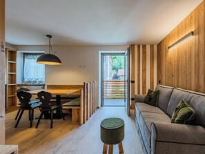 Ein modernes Interieur mit einem Essbereich aus Holz, einer Couch und einem kleinen runden Hocker.