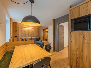 Eine moderne Küche mit Holzschränken, einem eingebauten Ofen und einem Essbereich mit Holztisch und -stühlen.