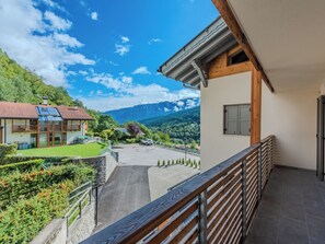 Ein Balkon mit Blick auf eine Berglandschaft, ein Parkplatz und ein Gebäude mit rotem Ziegeldach.