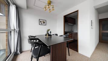 Un comedor moderno con una mesa rectangular, sillas negras, un florero decorativo y un cuadro en la pared.