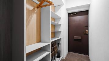 Un couloir avec une armoire en bois, des étagères blanches et une porte marron.
